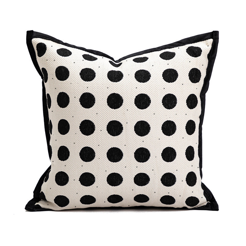 Decorative pillow with black polka dots on a white background