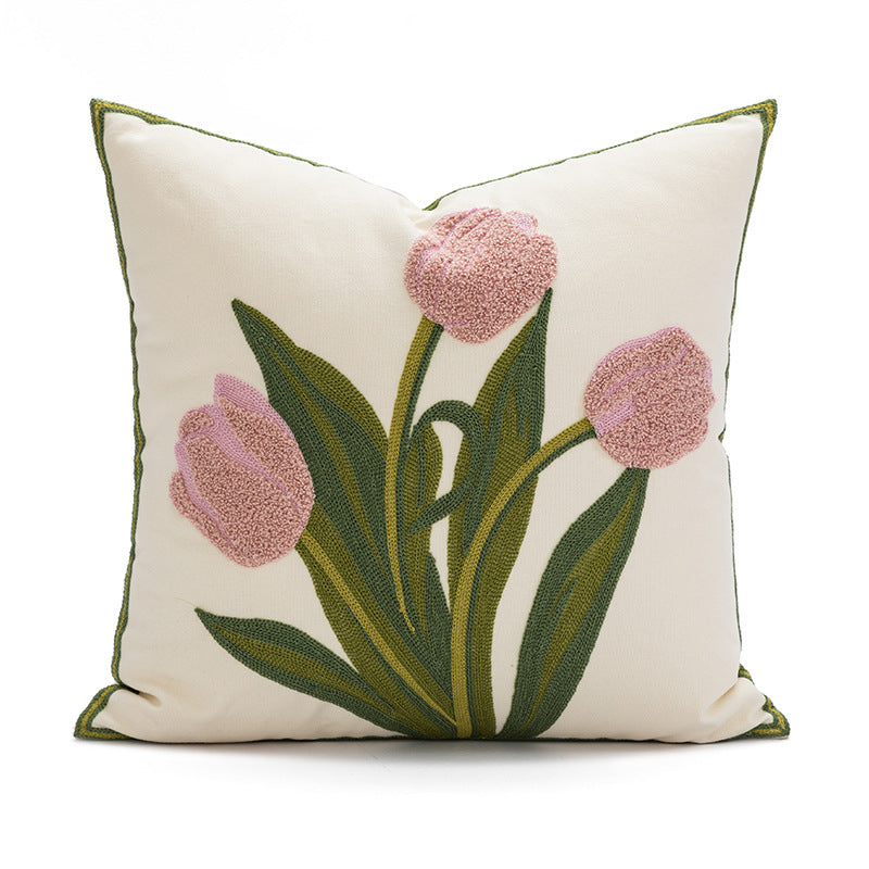 Decorative pillow with pink tulips and green leaves on a white background