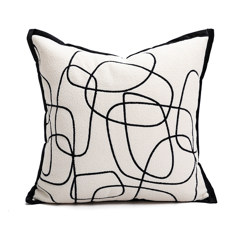 Decorative pillow with black abstract line design on a white background