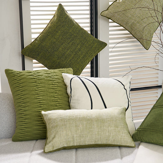 Green textured pillows on a sofa with a neutral background