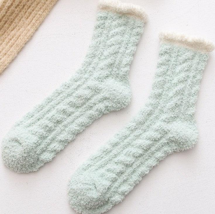 Pair of light green fuzzy socks on a white surface