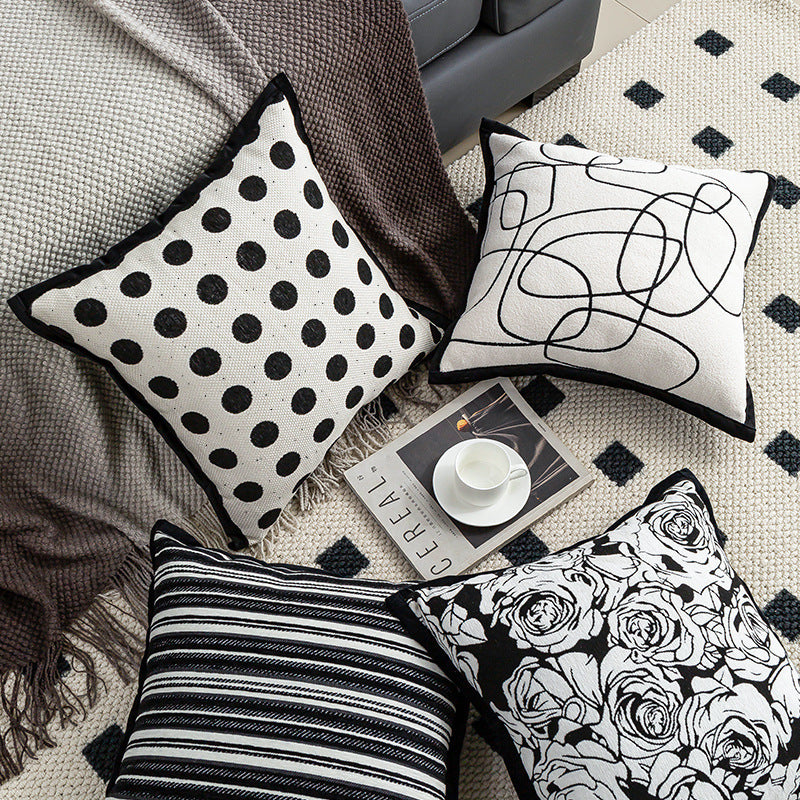 Black and white patterned cushions on a textured surface with a magazine underneath.