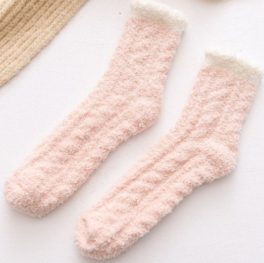 Pair of pink fuzzy winter socks on a light background