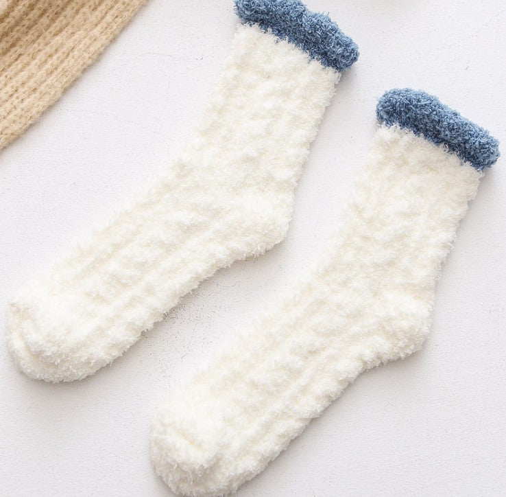 Pair of white socks with blue tips on a light background